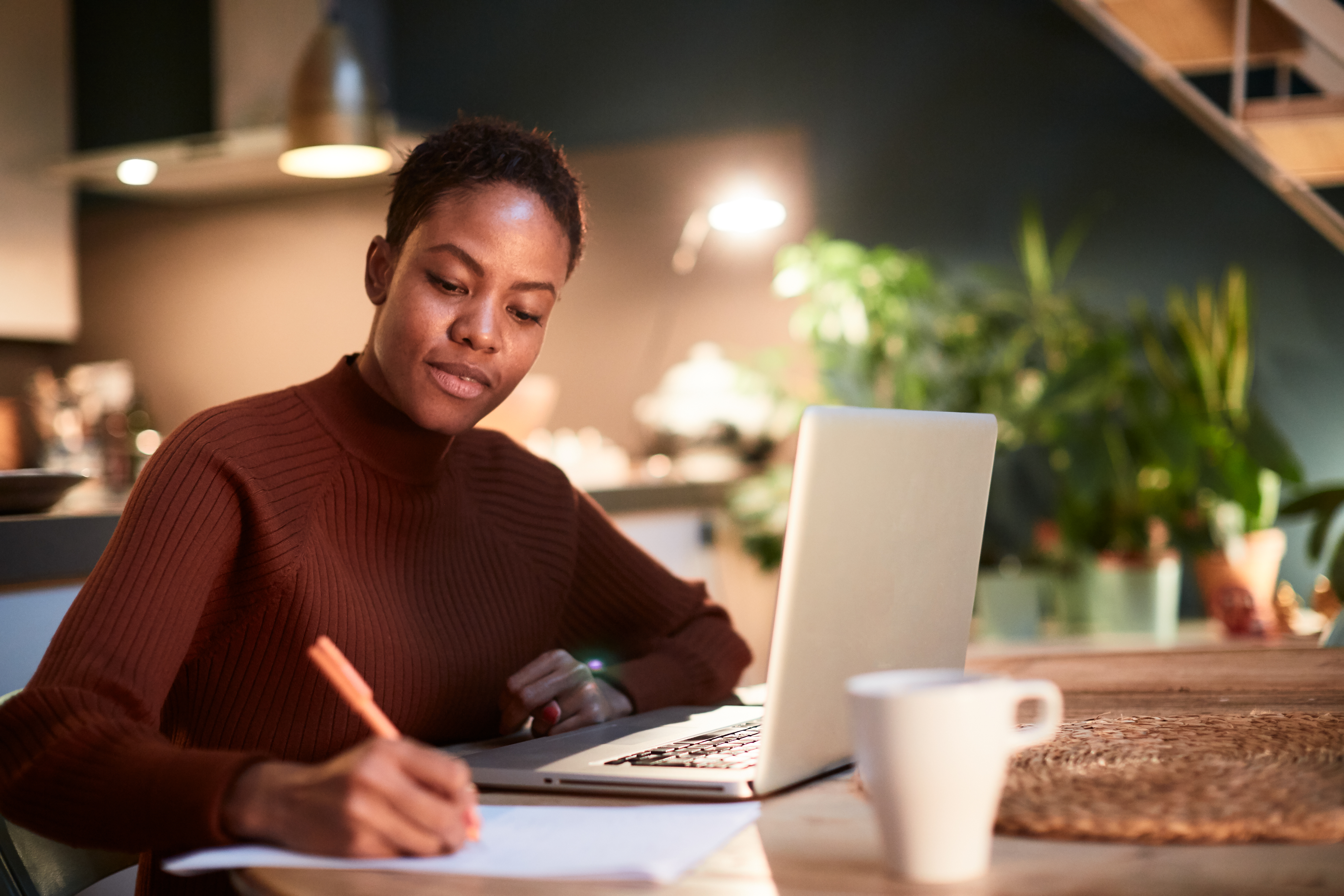 Woman making notes at a laptop